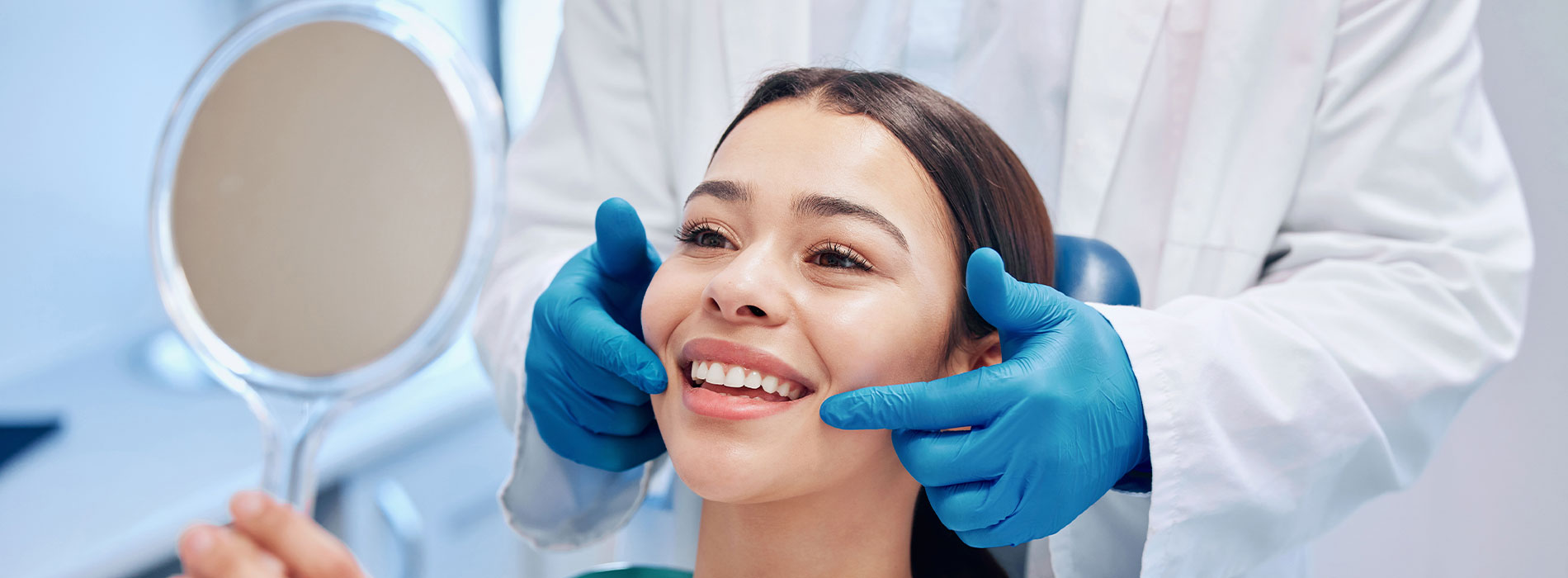 The image shows a woman sitting in a dental chair with her eyes closed, receiving a dental cleaning from a dentist wearing blue gloves and a white coat.