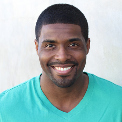 An elderly couple posing for a photo with smiles on their faces against a scenic backdrop.