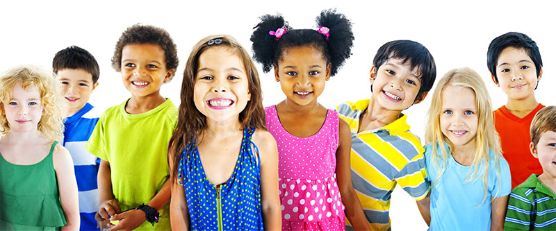 The image shows a group of children standing together with smiles on their faces, posing for a photo with various colors of clothing and accessories.