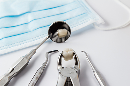 The image shows a collection of dental tools, including a toothbrush with toothpaste on it, placed next to a blue mask on a white surface.