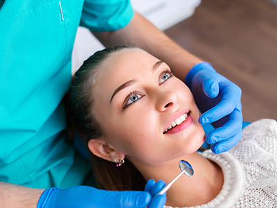 A person receiving dental care with a dentist s hand holding a mirror over their mouth.